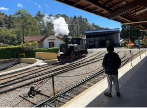 Criança observando o trenzinho turístico de Campos do Jordão durante passeio em família