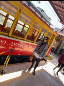 Mãe em viagem em família posando com o bondinho turístico ao fundo em Campos do Jordão