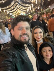 Família passeando à noite pela Vila Capivari em Campos do Jordão com dois adultos e uma criança durante viagem em família