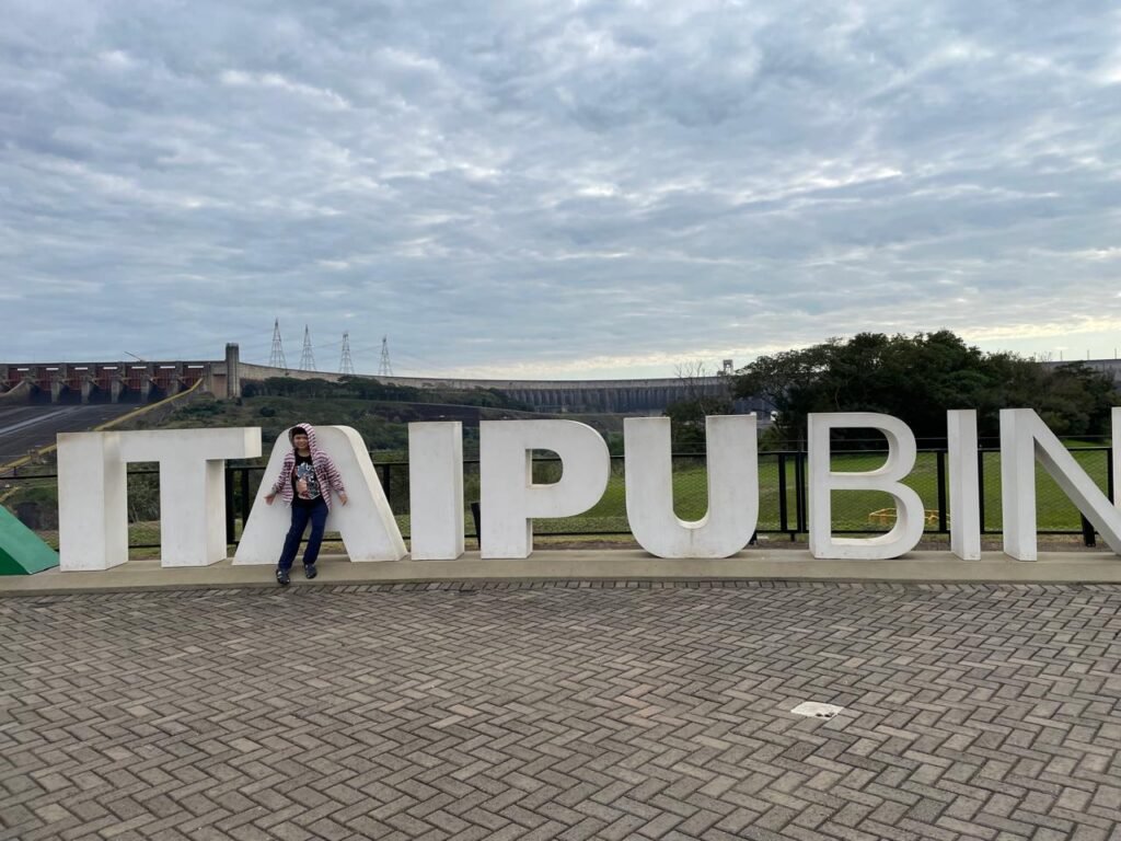 Foz do Iguaçu em 6 Dias: Roteiro Completo 5 Lucas posando em frente ao letreiro da Itaipu Binacional durante passeio em Foz do Iguaçu.