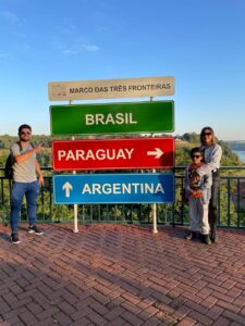 Glaziele, Rafa e Lucas posando em frente à placa do Marco das Três Fronteiras durante viagem em família a Foz do Iguaçu.