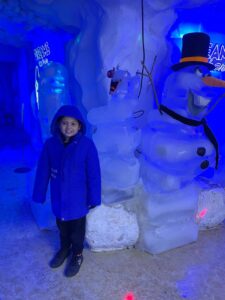 Lucas usando roupas térmicas dentro do Ice Bar em Foz do Iguaçu durante passeio em família.