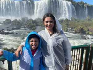 Glaziele e Lucas na passarela das Cataratas do Iguaçu, molhados pela névoa das quedas d'água durante passeio em família.
