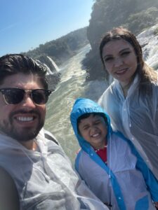Glaziele, Rafael e Lucas molhados na passarela das Cataratas do Iguaçu durante passeio em família.