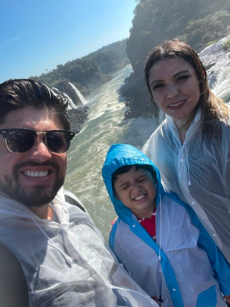 Glaziele, Rafael e Lucas molhados na passarela das Cataratas do Iguaçu durante passeio em família.
