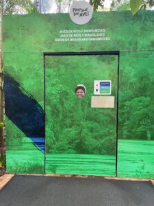 Lucas interagindo com uma placa educativa no Parque das Aves durante passeio em Foz do Iguaçu