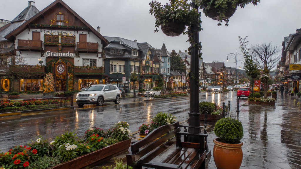 Rua de Gramado com chuva, flores e arquitetura típica