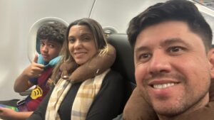 Família viajando de avião com criança autista usando travesseiro de pescoço durante o voo e conhecendo os direitos da pessoa autista em aeroportos.