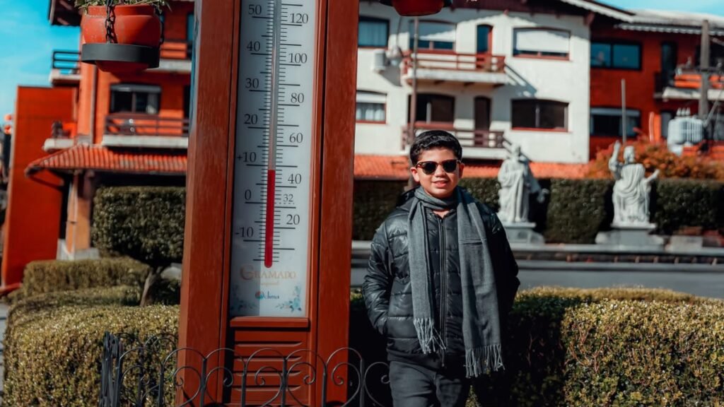 Lucas ao lado do termômetro em Gramado
