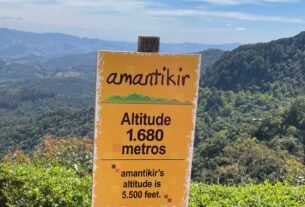 Placa do Parque Amantikir com indicação da altitude de 1.680 metros e vista das montanhas de Campos do Jordão