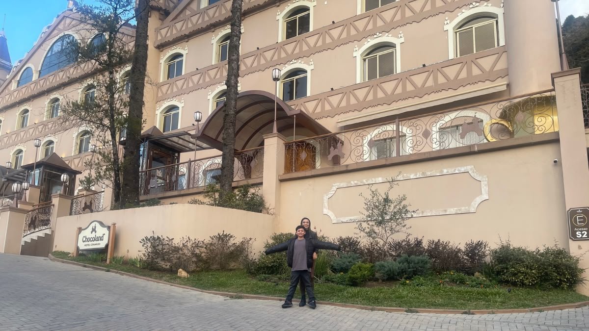Mãe e filho em frente a um hotel durante uma viagem em família