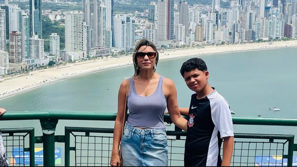 Mulher e criança diante da vista da orla e dos prédios de Balneário Camboriú.