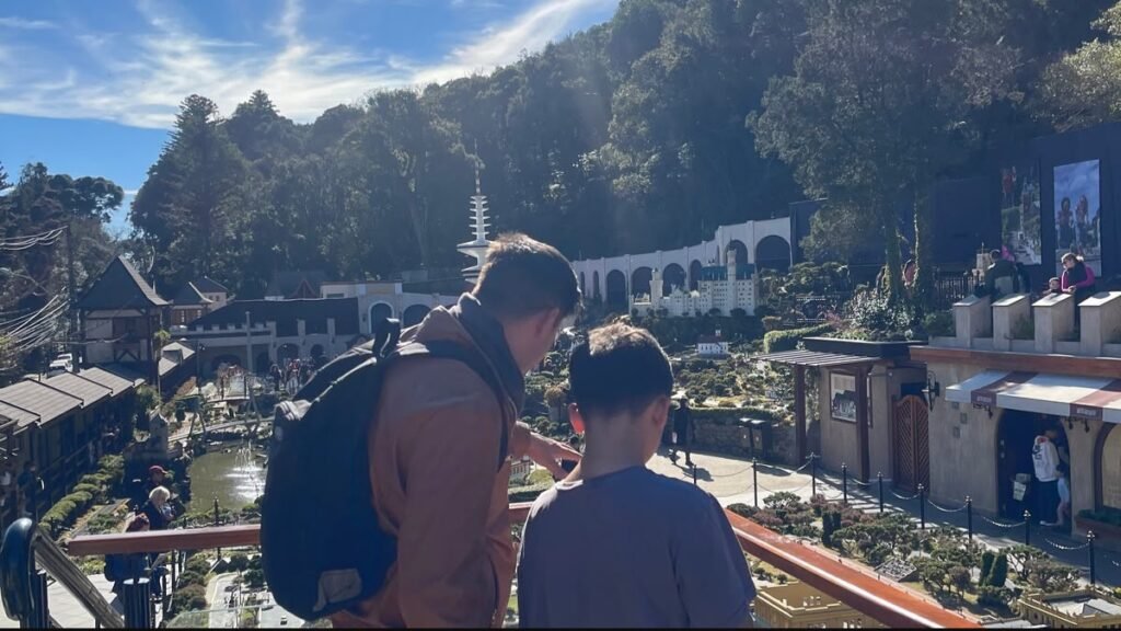 Rafael aponta para as miniaturas do Mini Mundo Gramado enquanto Lucas observa o cenário.