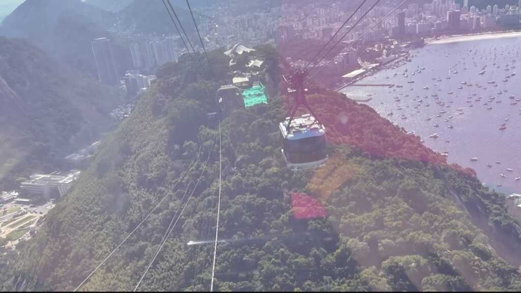 Teleféricos do Pão de Açúcar sobre a vegetação e a Baía de Guanabara, no Rio de Janeiro em um dia