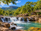 Rio com pequenas quedas d’água, vegetação e montanhas em Brotas