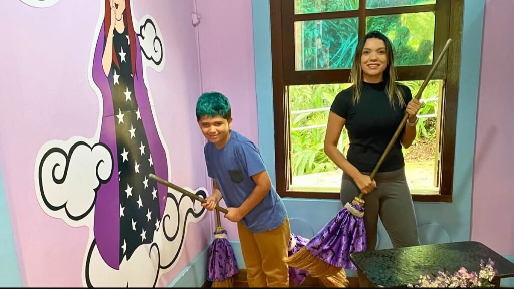 Curitiba com criança autista: mãe e filho seguram vassouras na Casa da Bruxa, no Bosque Alemão.