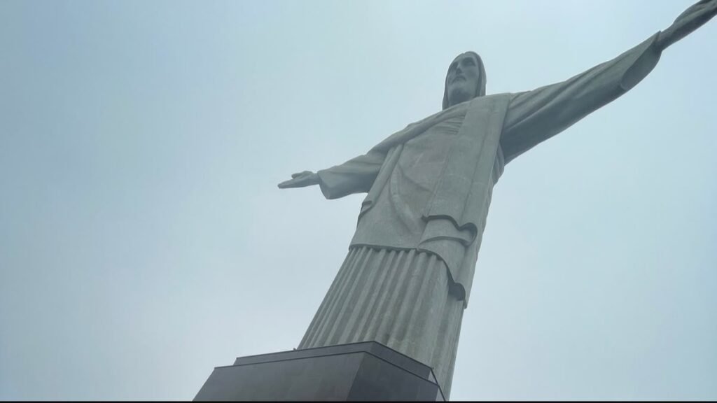 Estátua do Cristo Redentor fotografada de baixo, com os braços abertos no alto do Corcovado, no Rio de Janeiro.