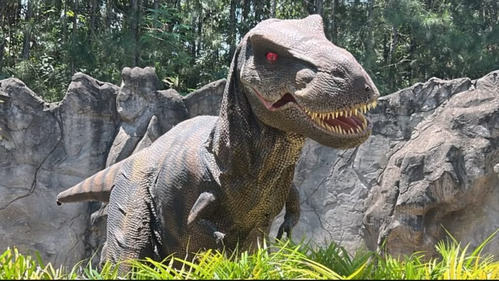 Dinossauro com olhos vermelhos em cenário rochoso no Acampark em Charqueada.