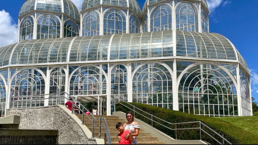 Curitiba com criança autista: estufa de vidro do Jardim Botânico cercada por jardins e caminhos.