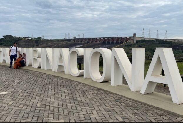 Família posa junto às letras Itaipu Binacional durante a visita à usina