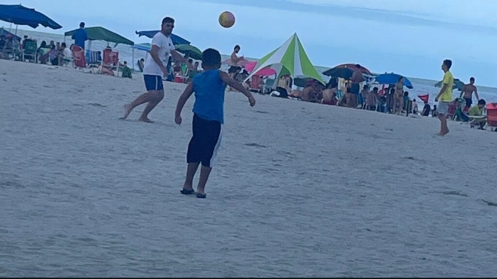 Rafa e Lucas jogando bola na areia da Praia Central de Balneário Camboriú durante um passeio em família.