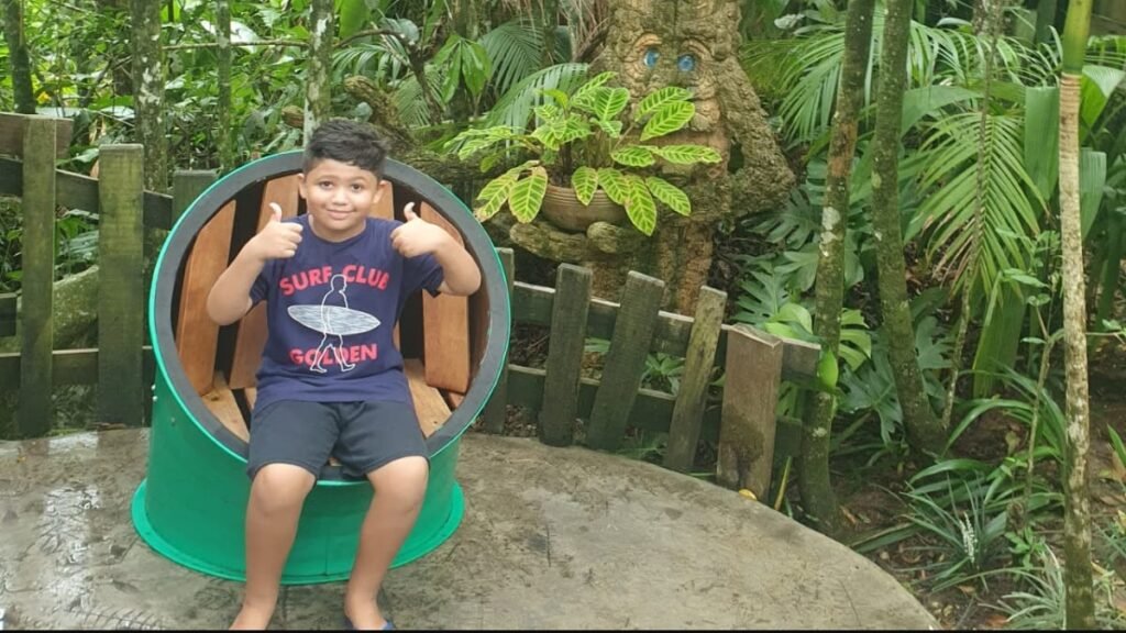 Lucas sentado em uma estrutura temática de madeira na Fantástica Floresta do Parque Unipraias.
