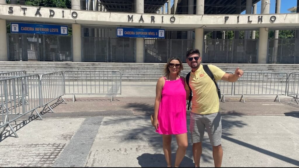 Casal em frente à entrada do Estádio Jornalista Mário Filho, conhecido como Maracanã, no Rio de Janeiro em um dia