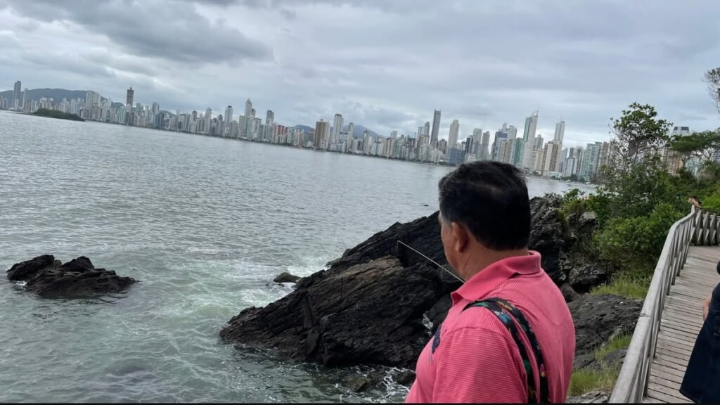 Passeios gratuitos em Balneário Camboriú: homem contemplando o mar e a paisagem dos prédios da cidade na Praia do Canto.