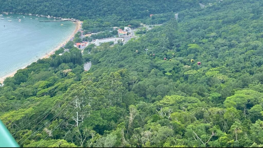Clima em Balneário Camboriú: melhor época para viajar e como é o tempo em cada estação 3 Vista panorâmica da Praia de Laranjeiras em Balneário Camboriú, com mar, Mata Atlântica e teleférico.
