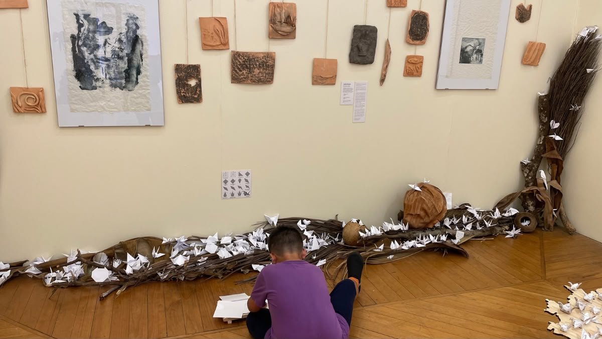 Lucas fazendo origamis durante visita ao Museu da Gravura em Curitiba