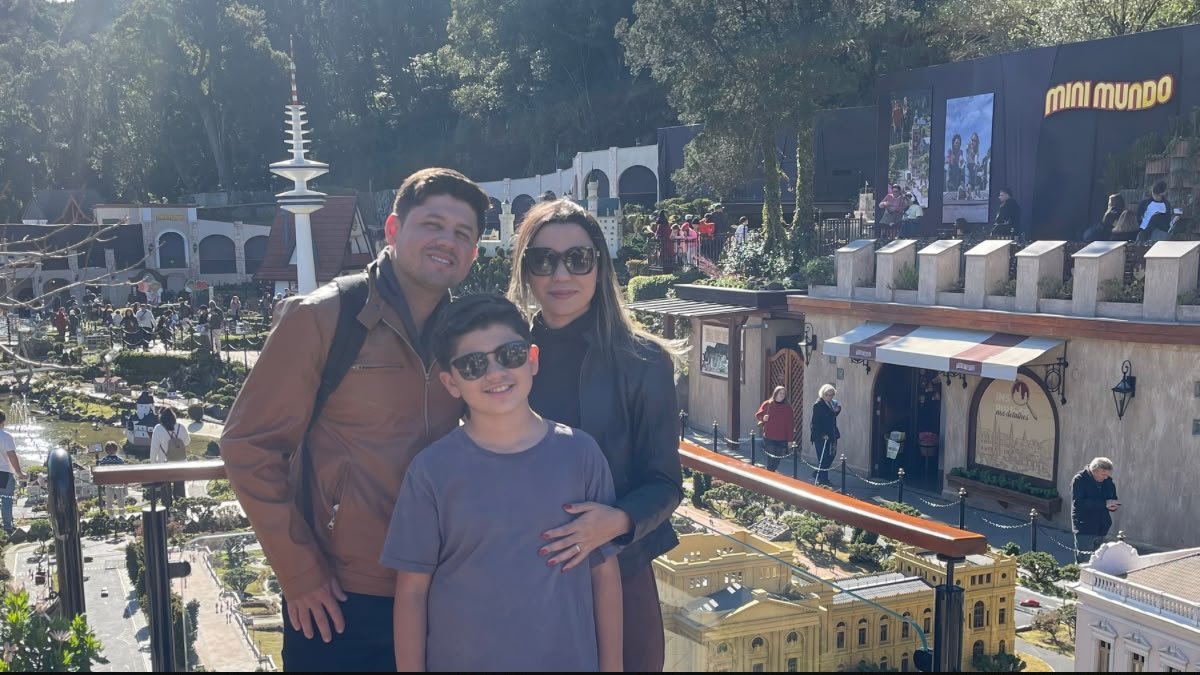 Família reunida no Mini Mundo Gramado, com construções em miniatura ao fundo.