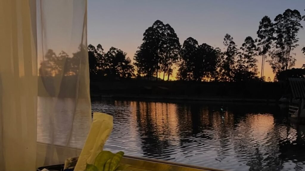 Hotel para autistas: como escolher uma hospedagem inclusiva 4 Paisagem com lago e árvores vista da janela de um hotel ao entardecer