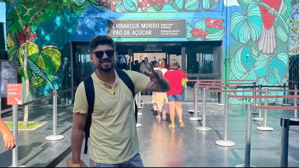 Homem posando na entrada da estação do Bondinho Pão de Açúcar, na Praia Vermelha, no Rio de Janeiro.