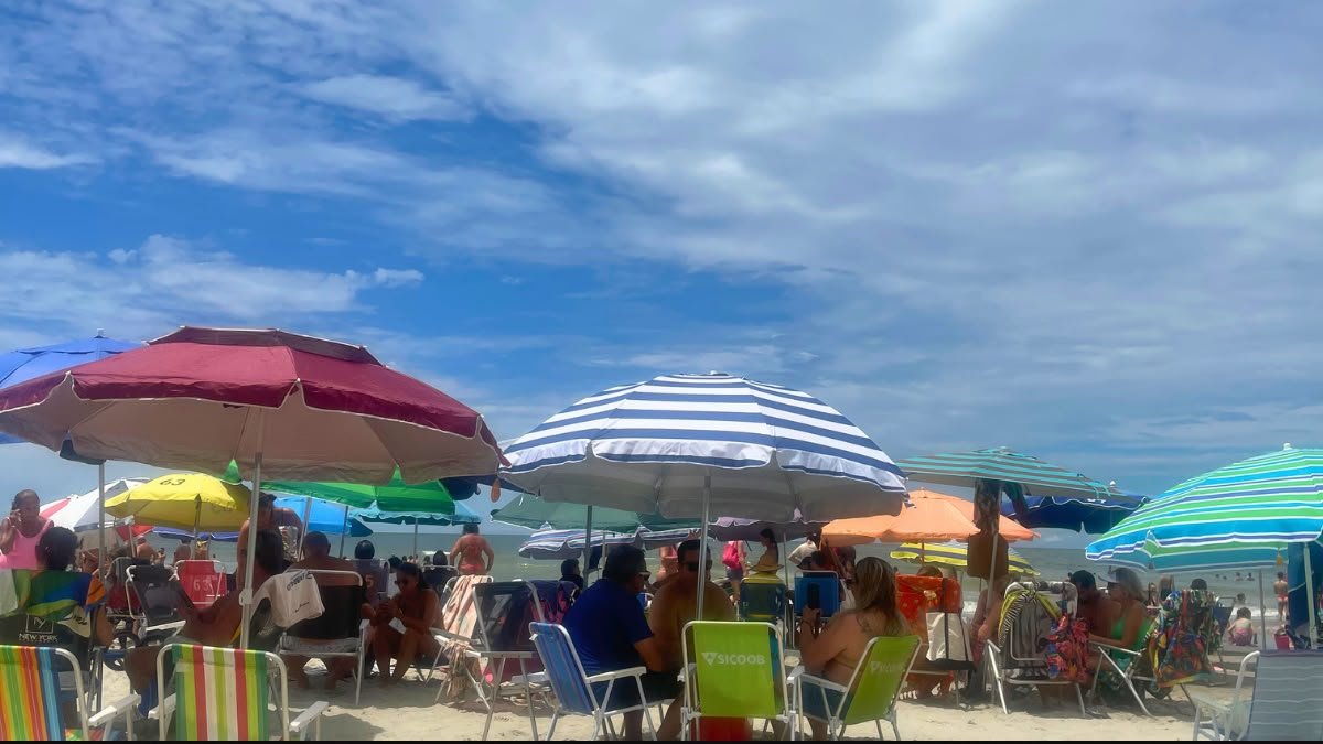 Clima em Balneário Camboriú: melhor época para viajar e como é o tempo em cada estação 1 Clima em Balneário Camboriú no verão, com céu parcialmente nublado, guarda-sóis e praia movimentada.