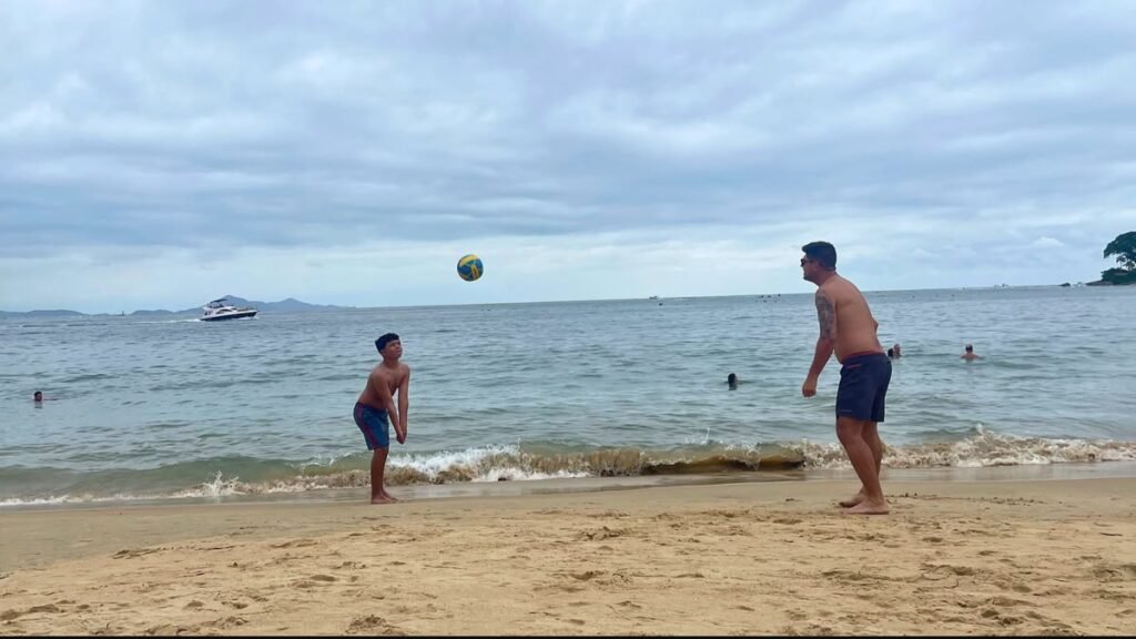 Pai e filho brincam com uma bola na água da Praia de Laranjeiras, em Balneário Camboriú.