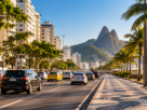 Avenida movimentada do Rio de Janeiro com carros e táxis diante dos Dois Irmãos