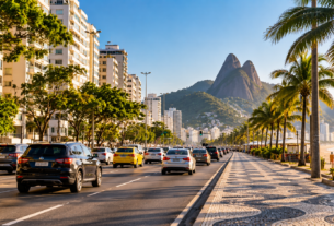 Avenida movimentada do Rio de Janeiro com carros e táxis diante dos Dois Irmãos