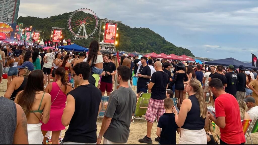 Público reunido em um show de Carnaval na Praia Central de Balneário Camboriú, com a roda-gigante ao fundo.