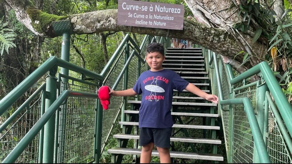 Criança na escadaria da trilha ecológica do Parque Unipraias, cercada pela vegetação da Mata Atlântica.