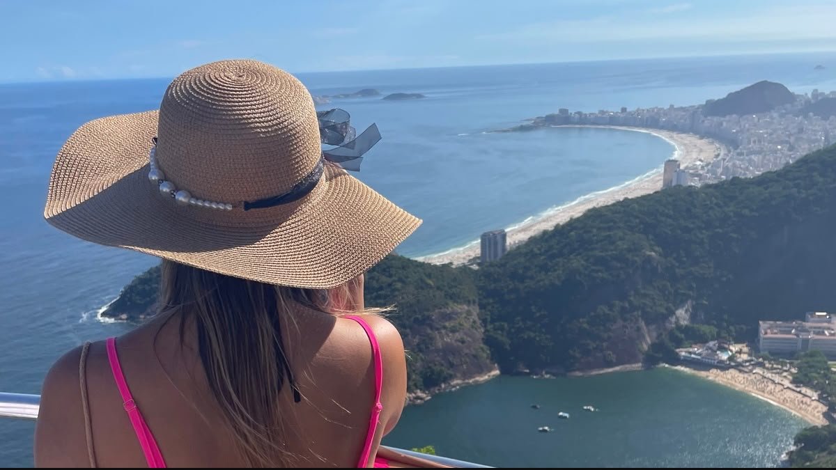 Mulher de chapéu observando o litoral do Rio de Janeiro do alto do Pão de Açúcar. Passeio rio de janeiro em um dia