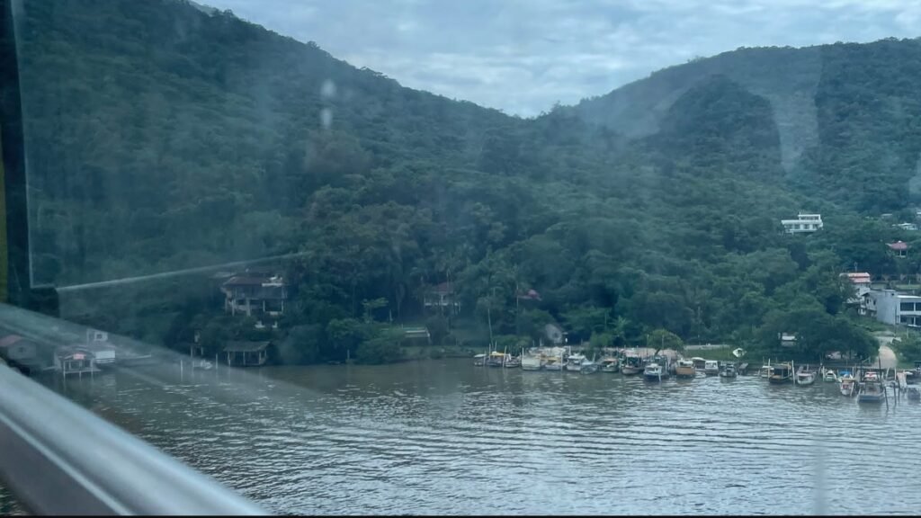 Vista do rio, de barcos e das encostas verdes durante o trajeto de bondinho no Parque Unipraias.